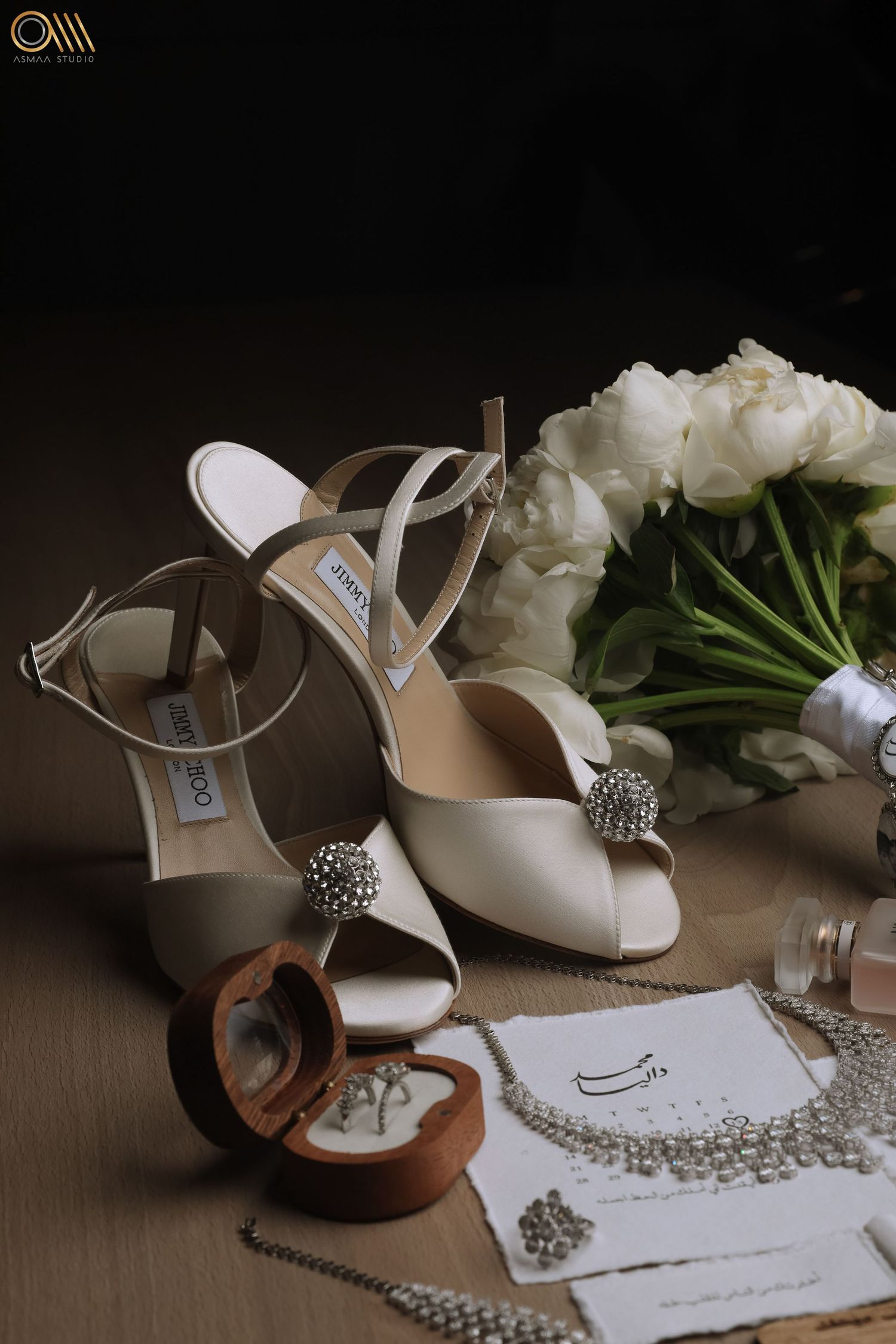 Bridal shoes and jewelry displayed with handwritten wedding stationery and floral elements.