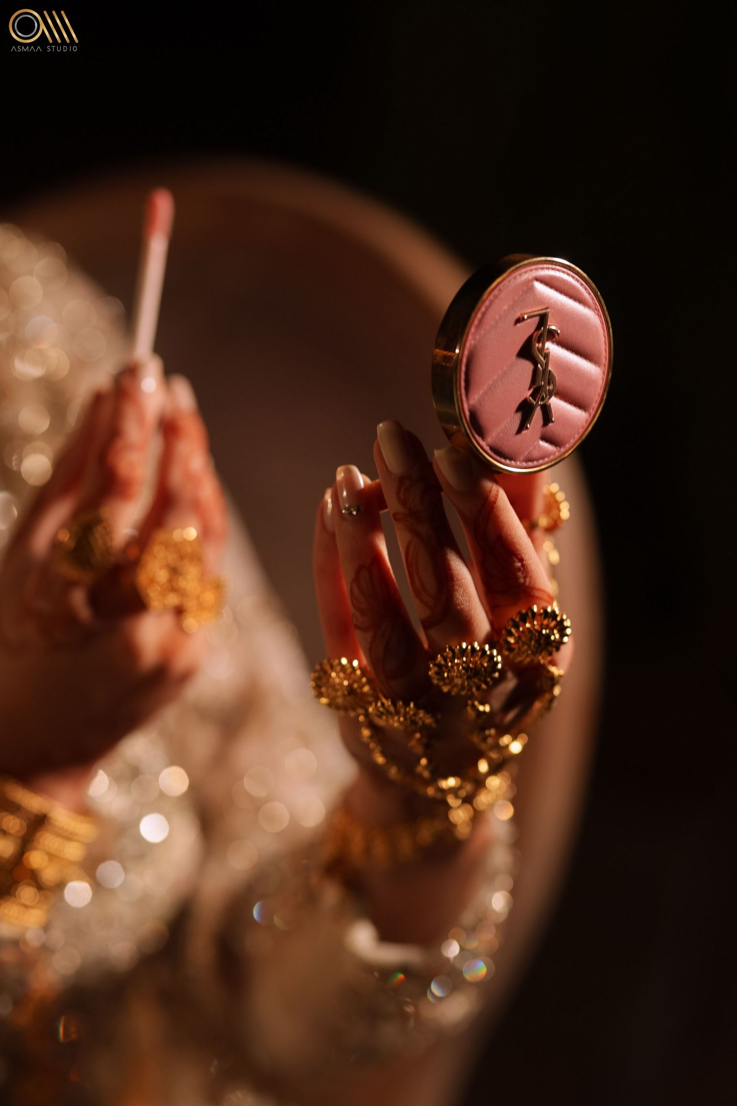 Decorative medallion held by hands adorned with golden jewelry.