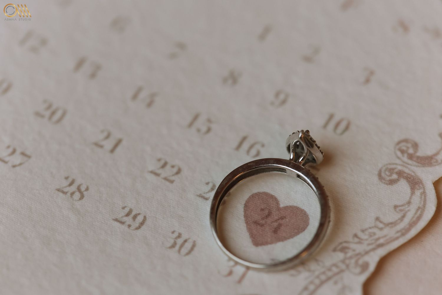 Silver engagement ring photographed on a vintage calendar page with romantic details.