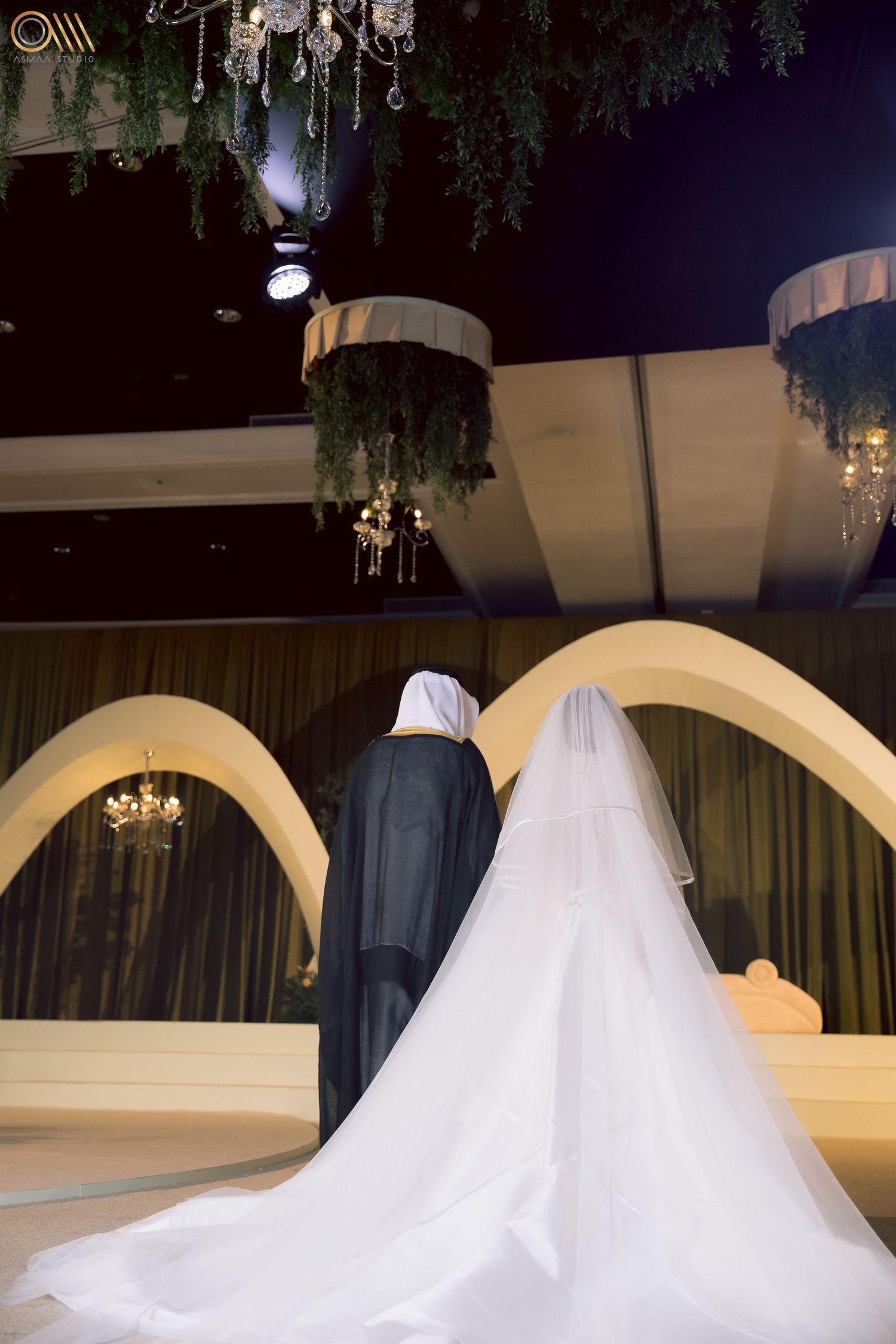 Wedding scene at night with arched architecture and flowing white dress under decorative lighting.