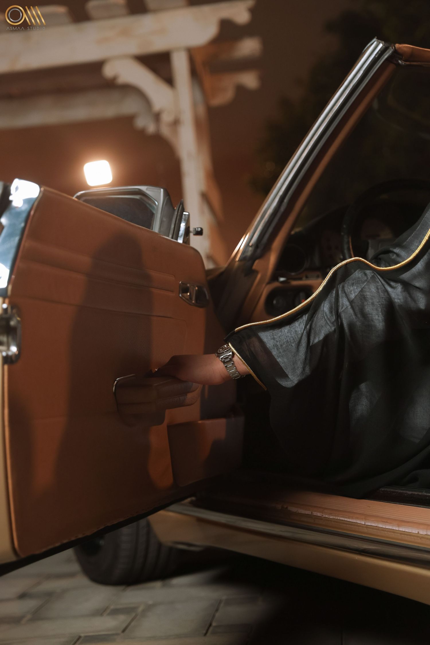 Car door handle detail in warm lighting with leather interior visible.
