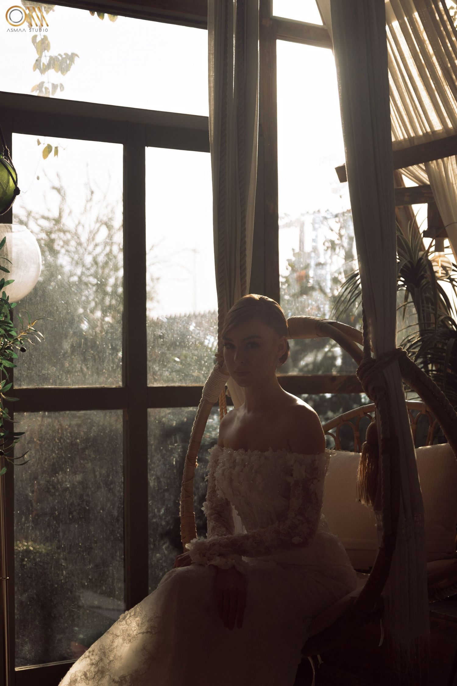 Wedding dress silhouettes captured against window light in a room with sheer curtains.