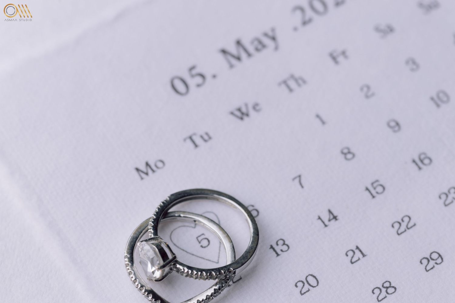 Wedding rings placed on a calendar page marking an important date.
