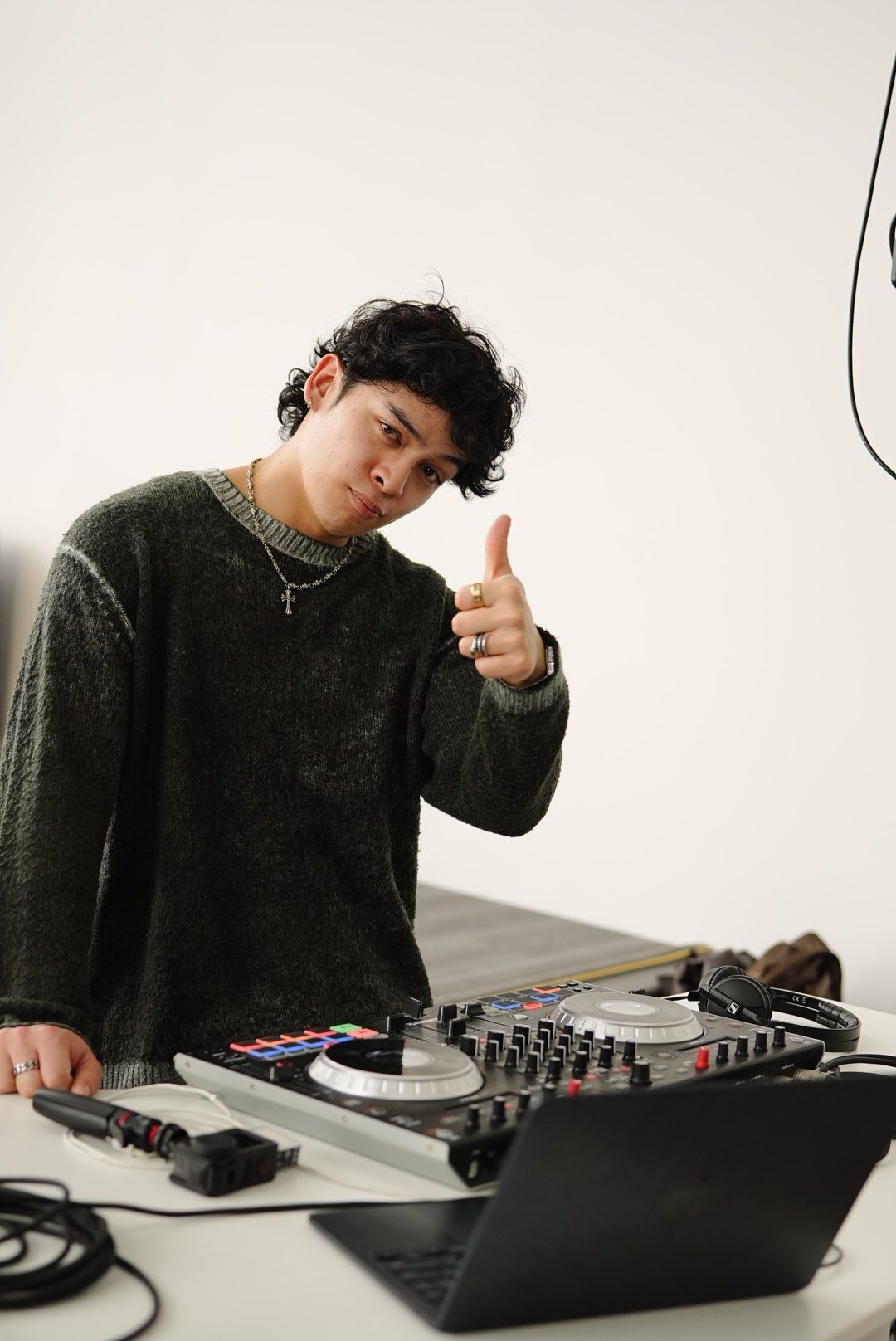 DJ giving thumbs up while working with mixer equipment and laptop.