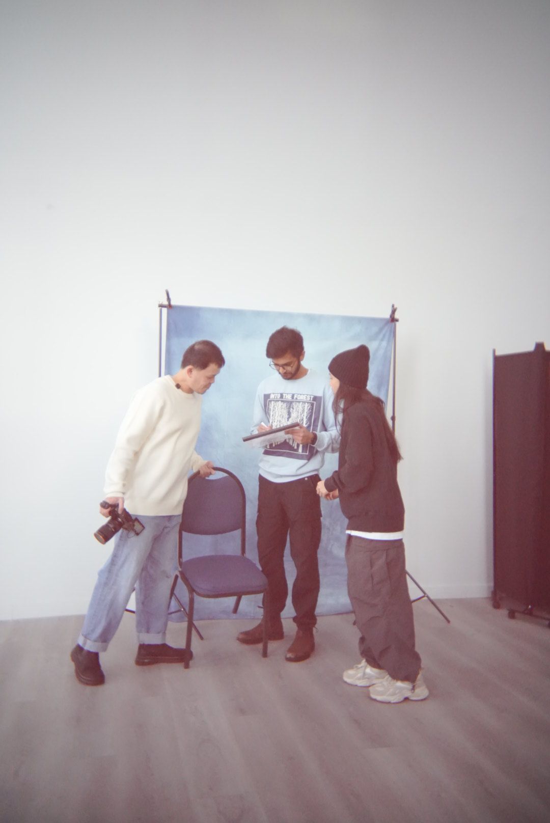 Group reviewing something together in front of blue photo backdrop in studio setting.
