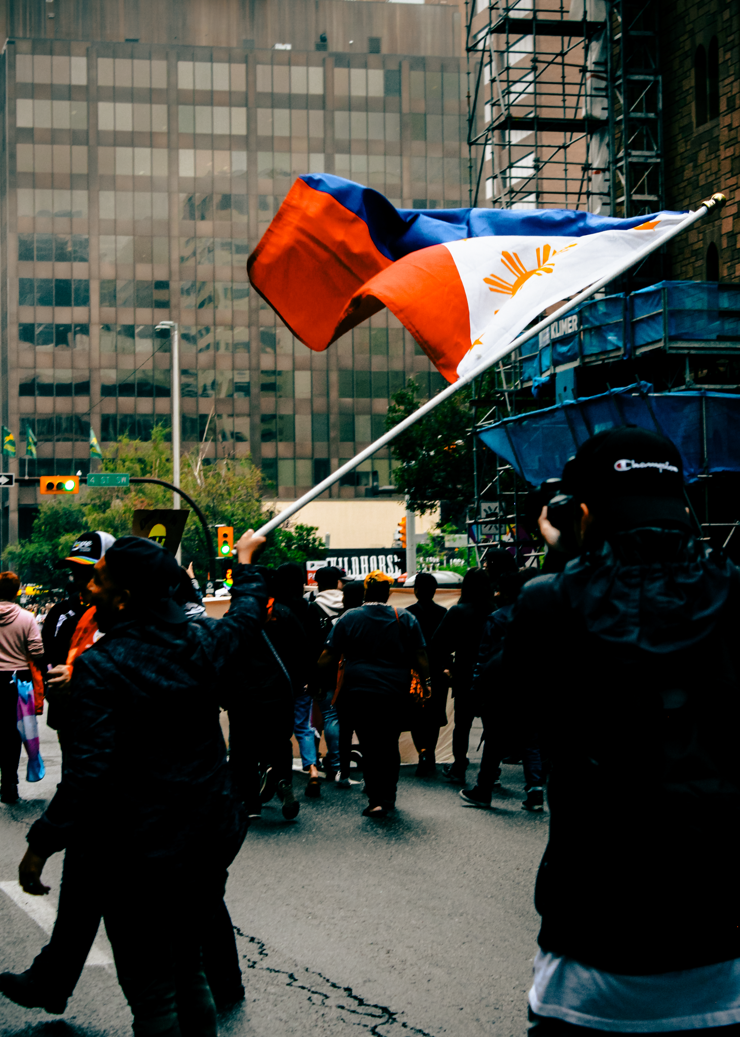 Group of protesters waving flags in front of a glass office building during an urban demonstration.