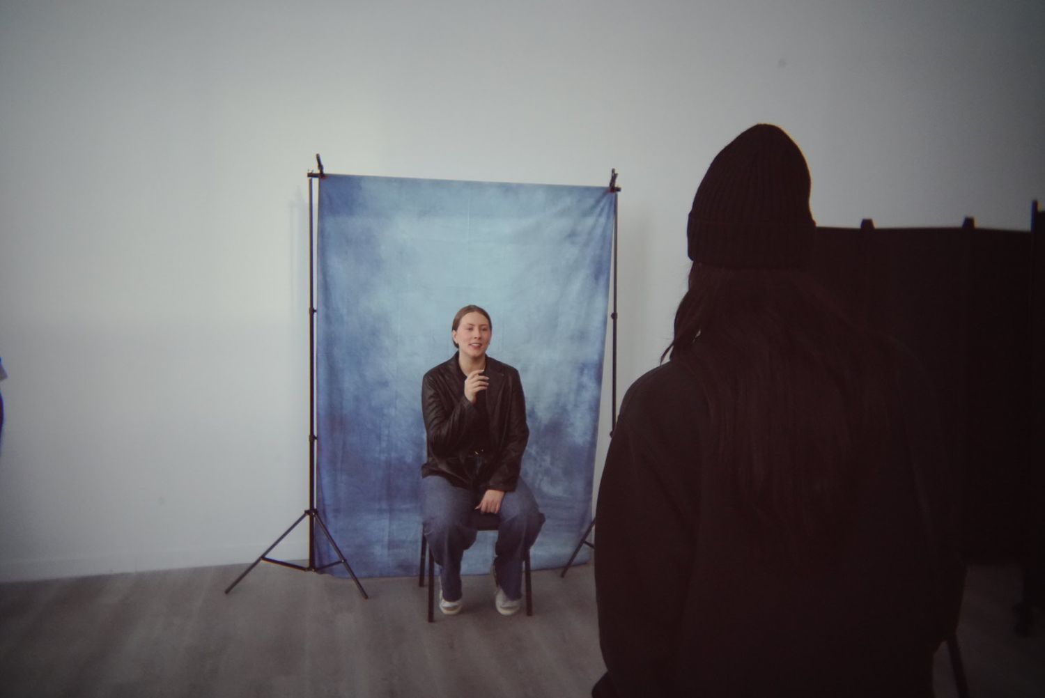 Studio portrait setup with blue backdrop and lighting equipment in minimalist setting.