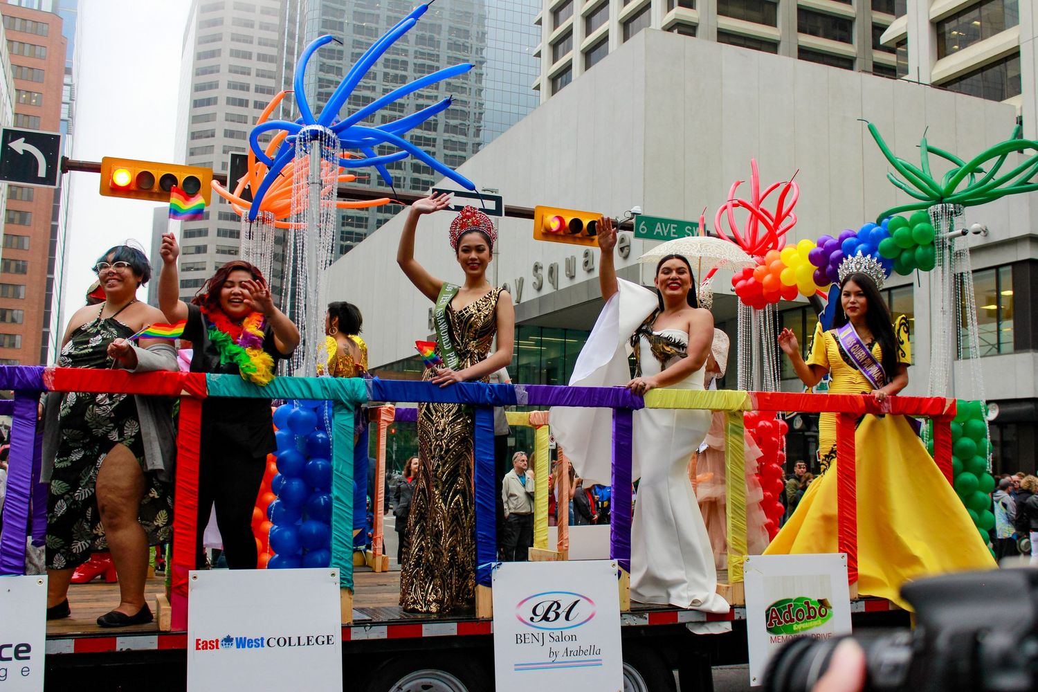 Colorful carnival parade with vibrant feathered costumes and decorations moving through a city street.