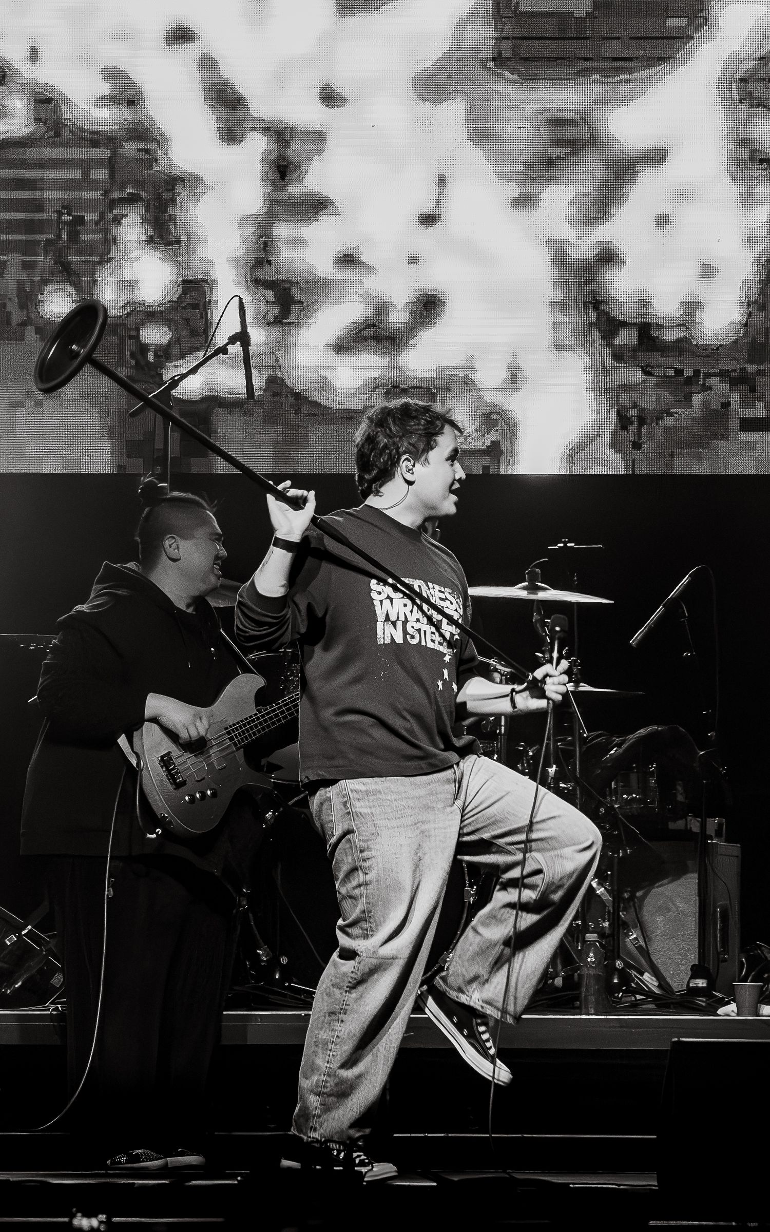 Dramatic black and white performance shot of band members on stage with dramatic lighting.