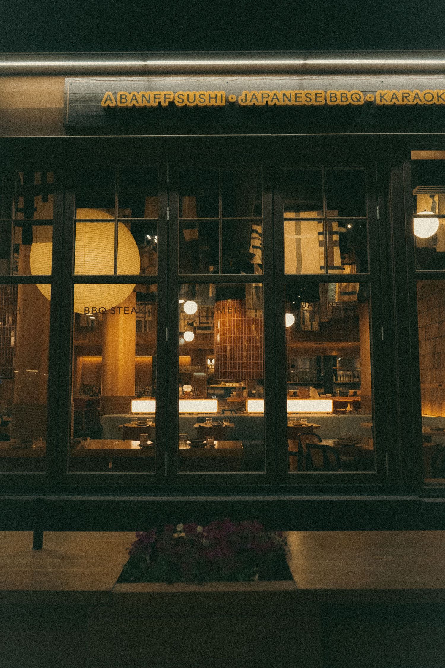Exterior view of a Japanese restaurant storefront with illuminated windows at night.