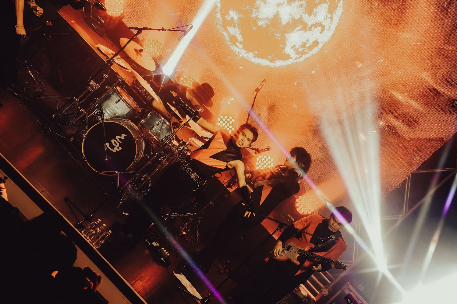 Concert venue with bright orange stage lighting and beam effects creating an energetic atmosphere.