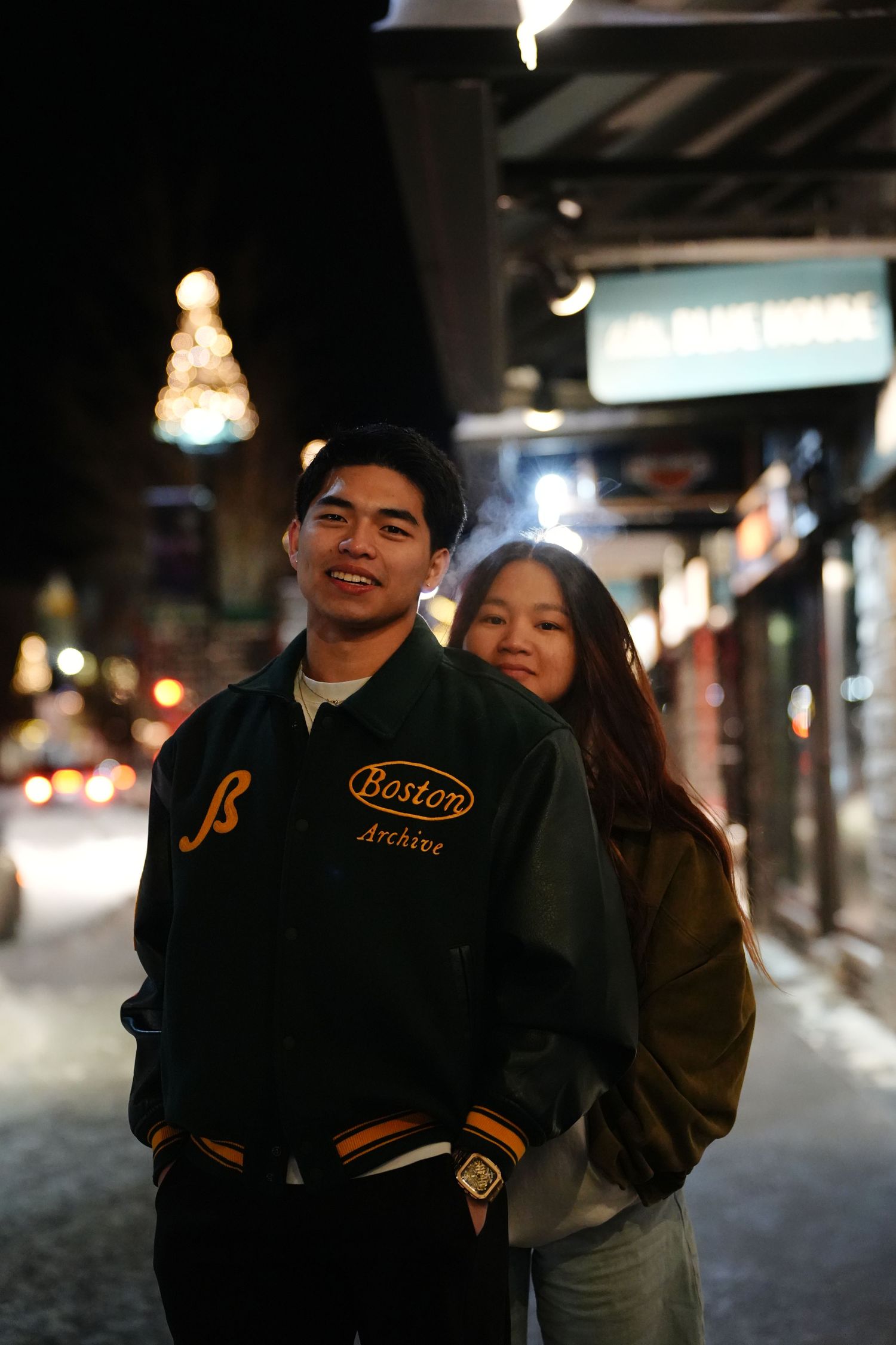 People in varsity jackets gather together on a dimly lit street at night.