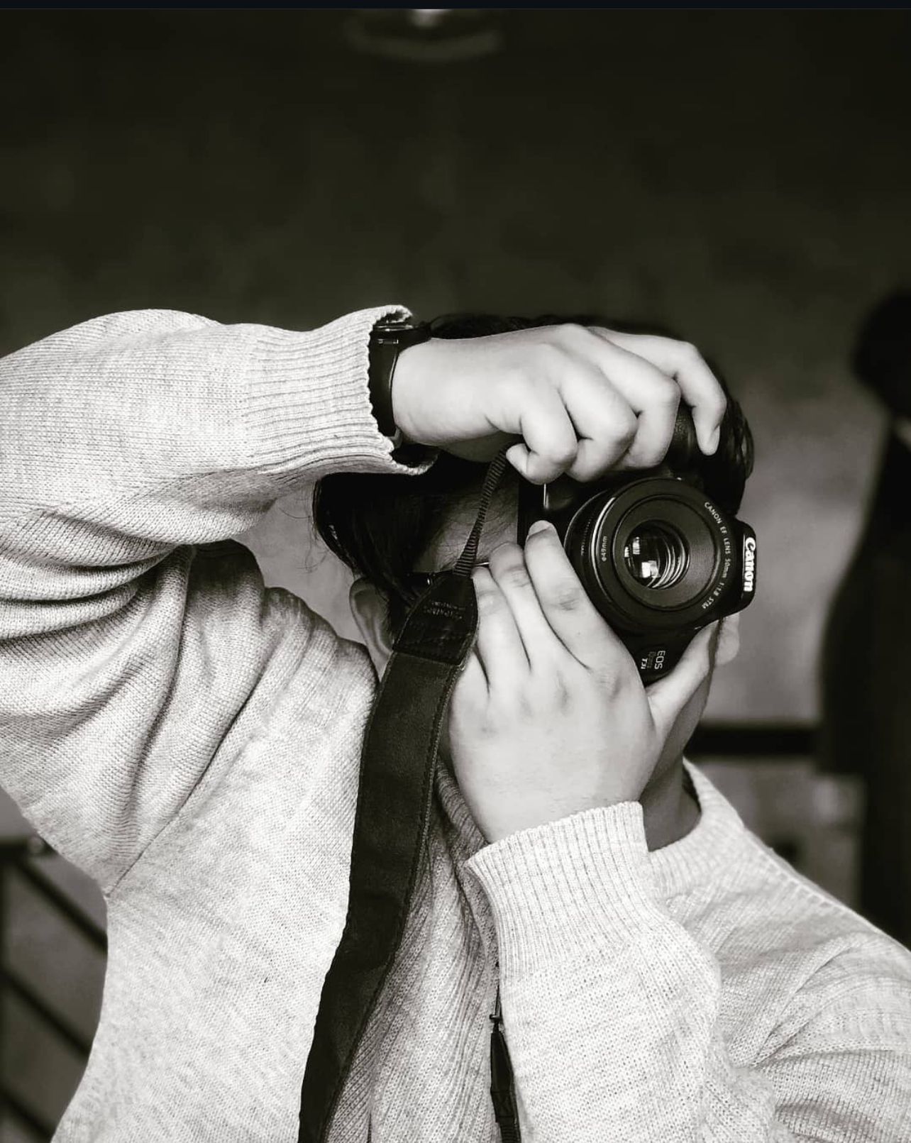 Close-up sequence of hands holding and operating a camera in black and white.