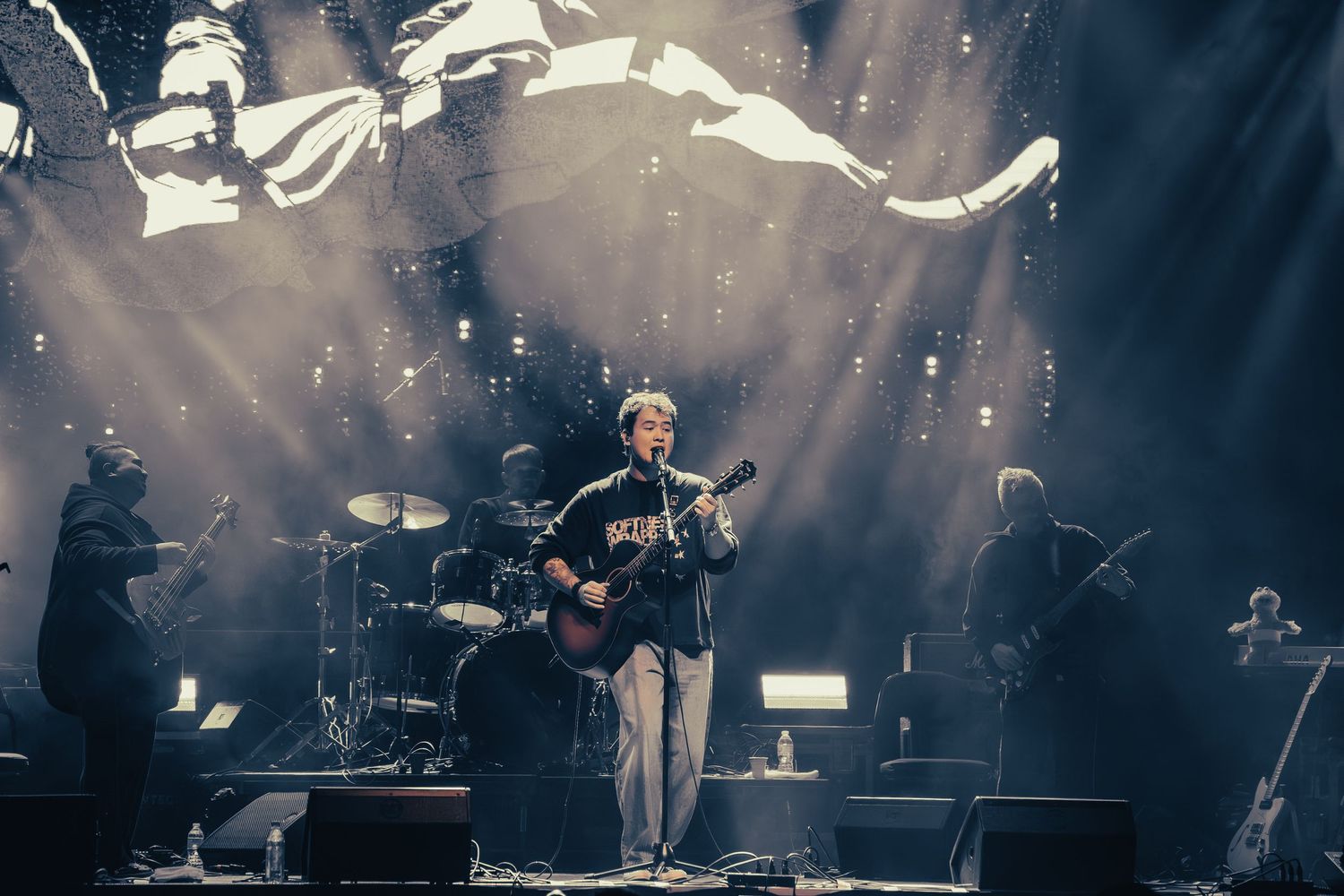 Dramatic concert performance with moody lighting and fog effects on a dark stage.