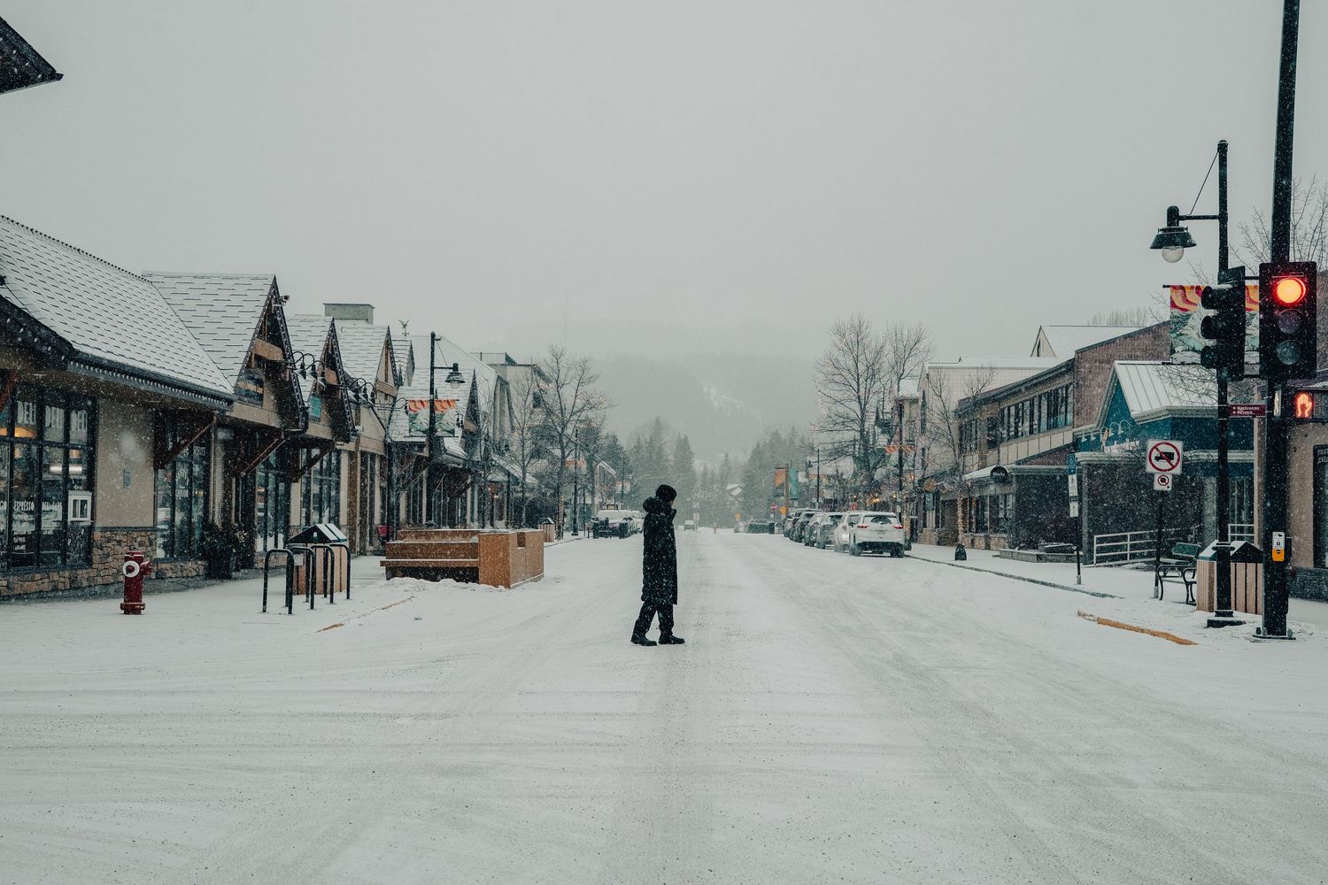 Snow-covered small town street with buildings and shops in winter conditions.