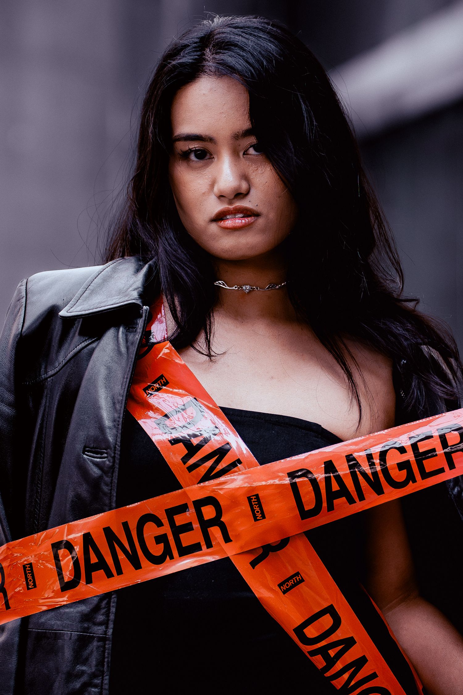 Edgy fashion portrait series with danger tape and leather jacket creating rebellious mood.