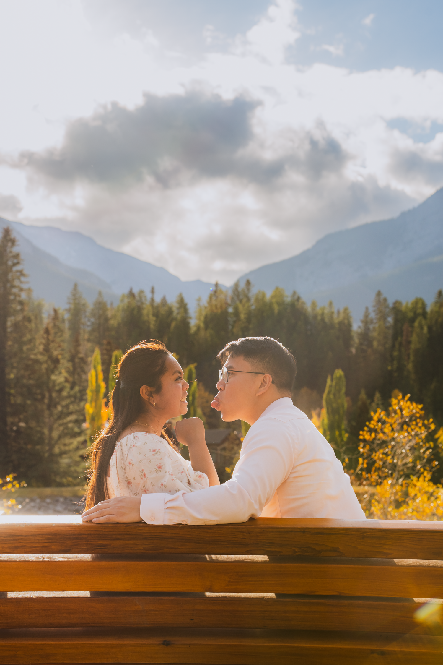 A romantic photoshoot at sunset with mountains and golden wildflowers in the background.