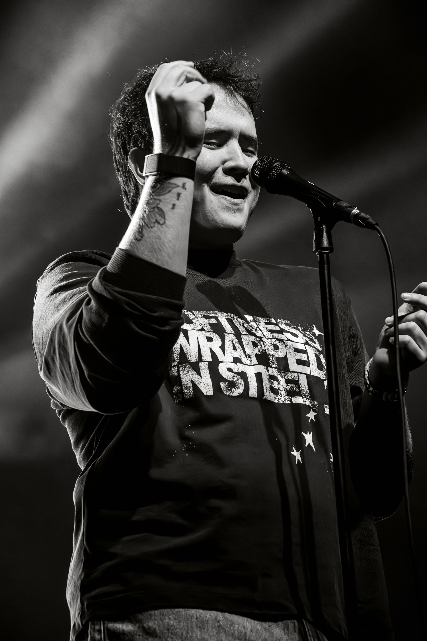 Black and white concert photos show a performer in dramatic lighting singing into a microphone on stage.
