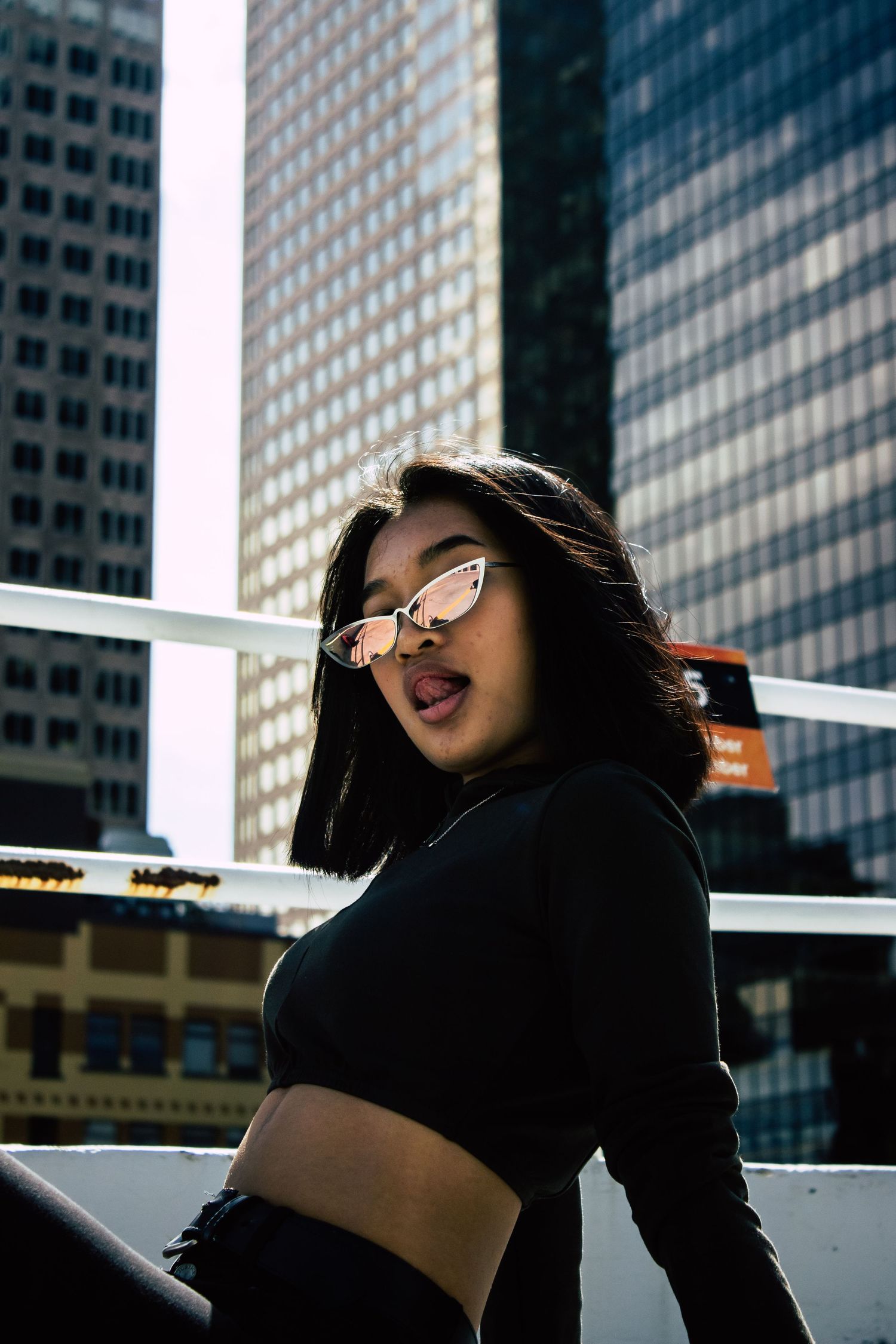 Urban fashion shoot against modern glass skyscrapers in bright sunlight.