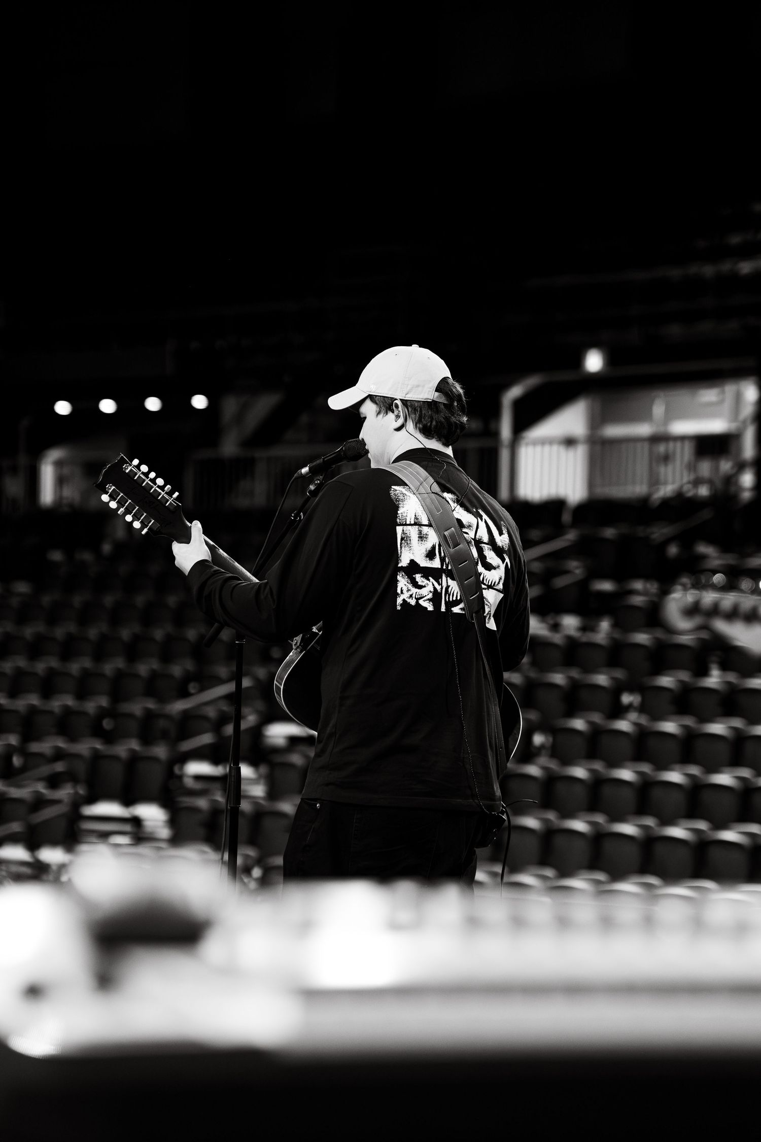 Silhouetted performer with guitar on stage in dramatic black and white lighting.
