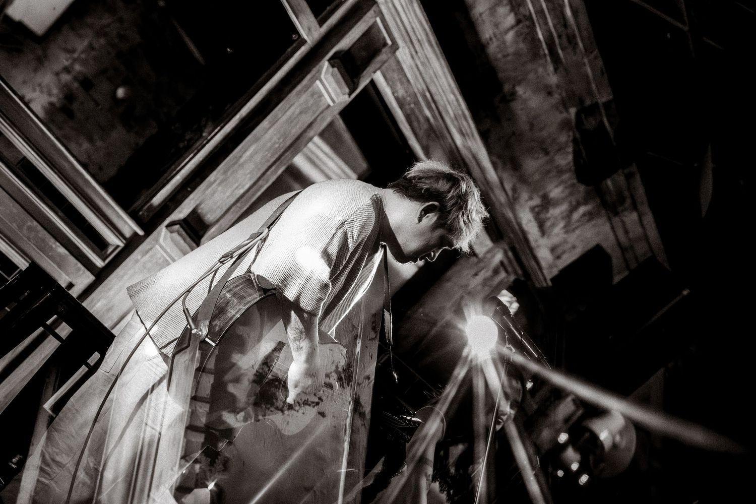 Black and white performance photo with dramatic stage lighting.