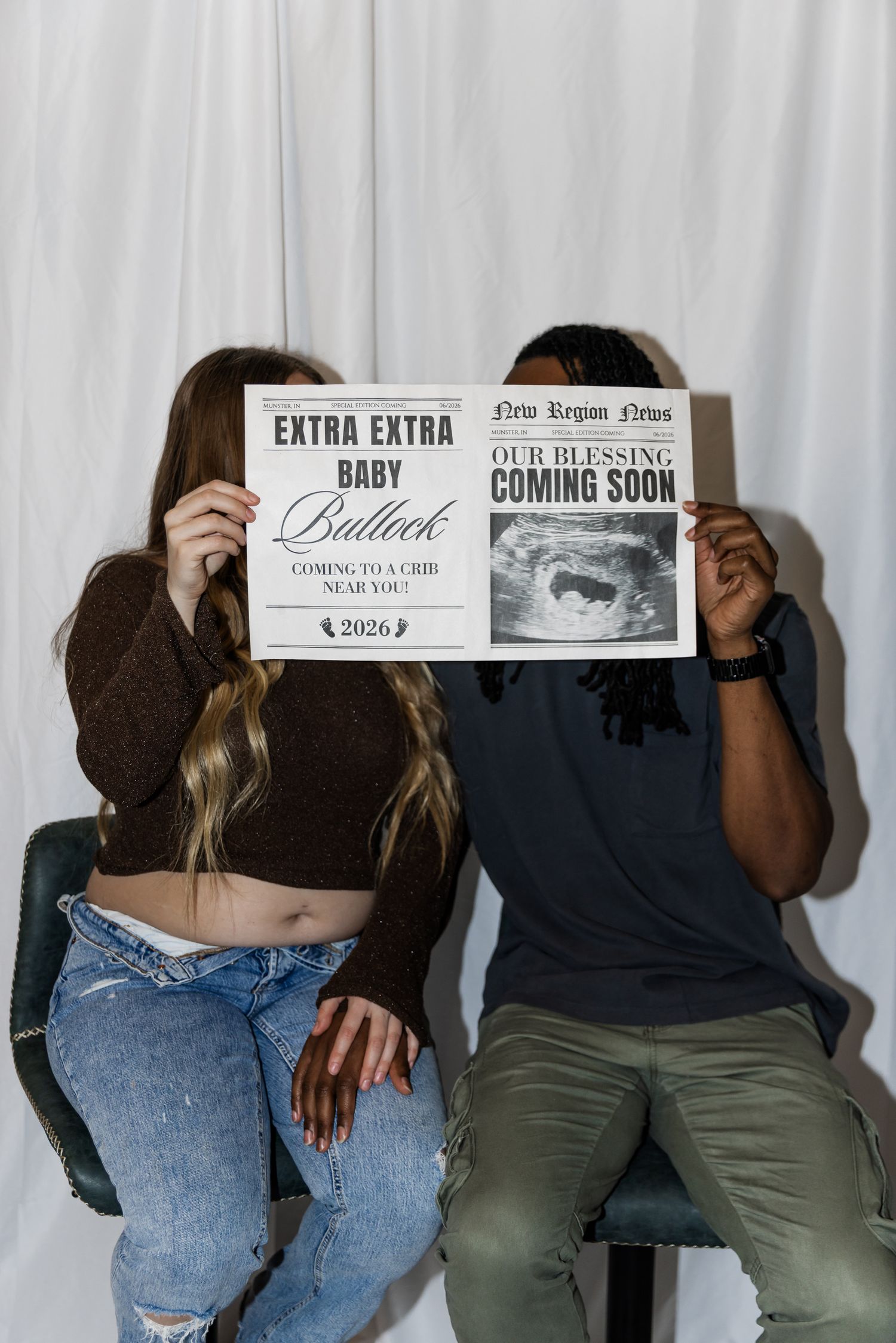 Couple holding pregnancy announcement newspapers with ultrasound photo and Baby Bullock coming 2026 sign.