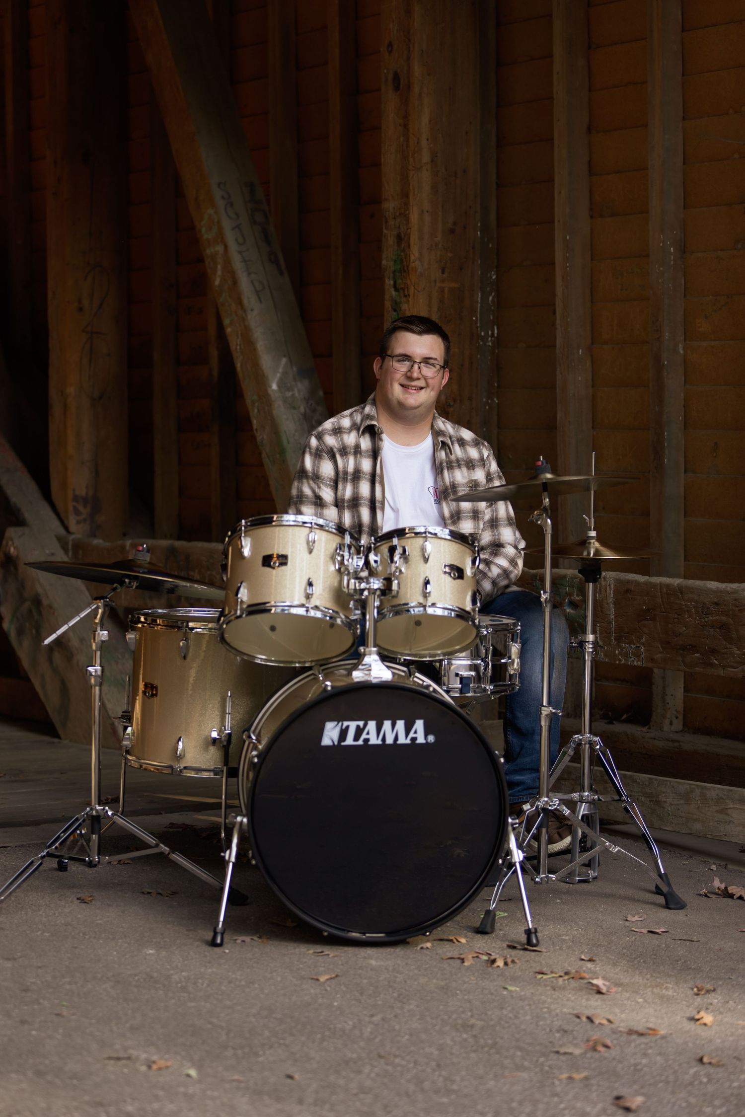 A drum set setup featuring a Tama brand drum kit in a rustic wooden space.