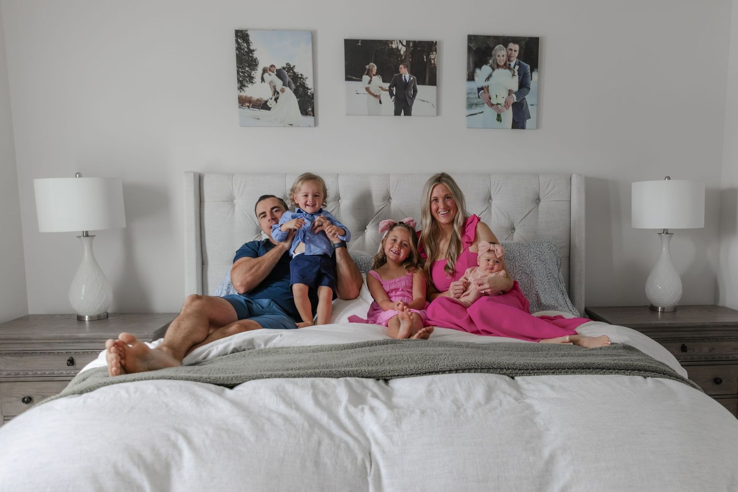Family relaxing together on a large white bed during an indoor photoshoot.