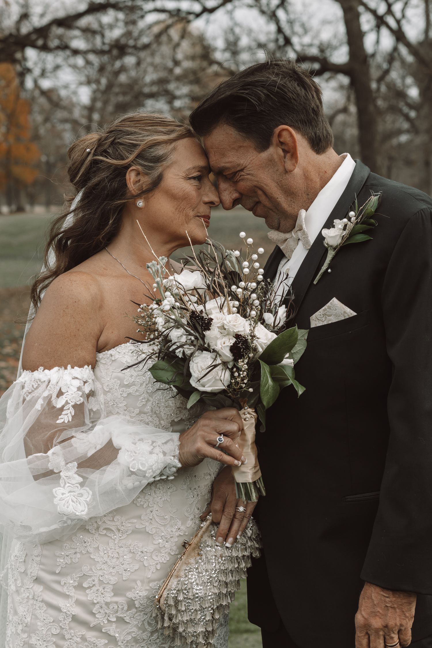 Romantic outdoor wedding portraits with white floral bouquet and formal attire.