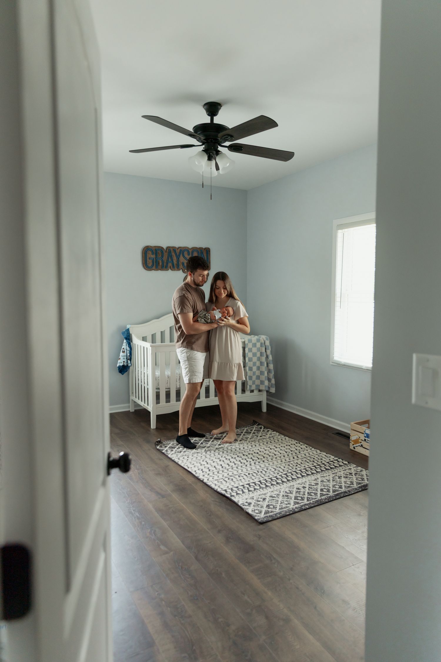 Modern nursery room with white crib, patterned rug, and hardwood floors.