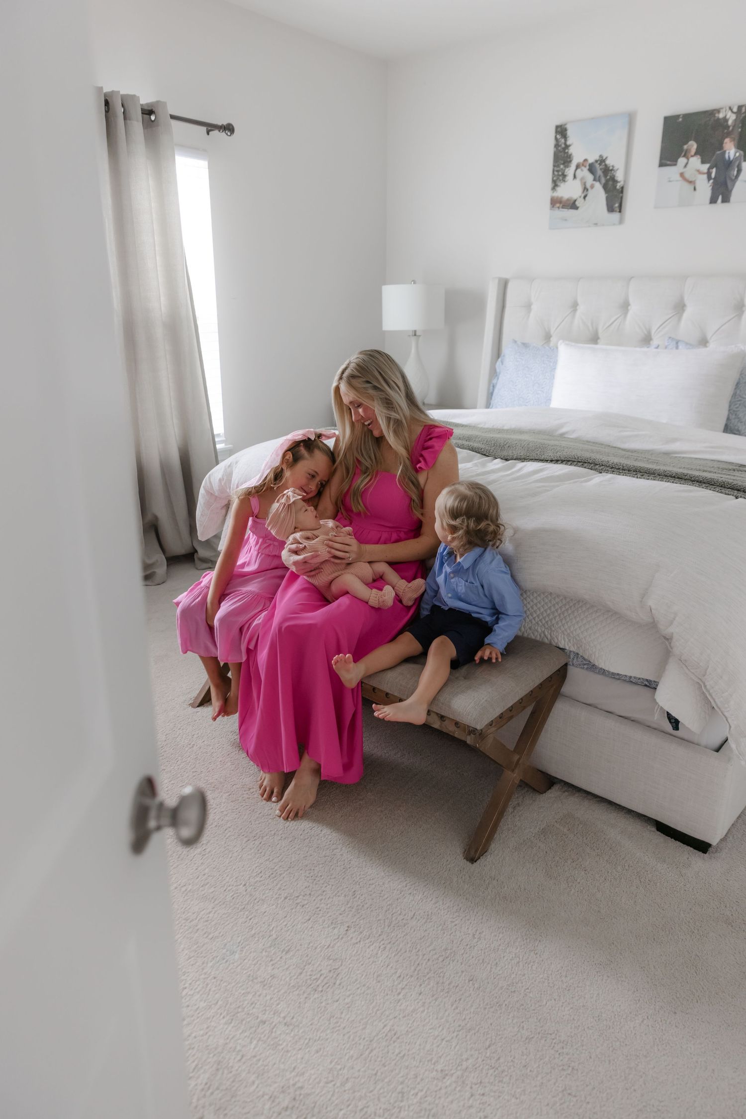 Family relaxing together on white bed in bright modern bedroom.