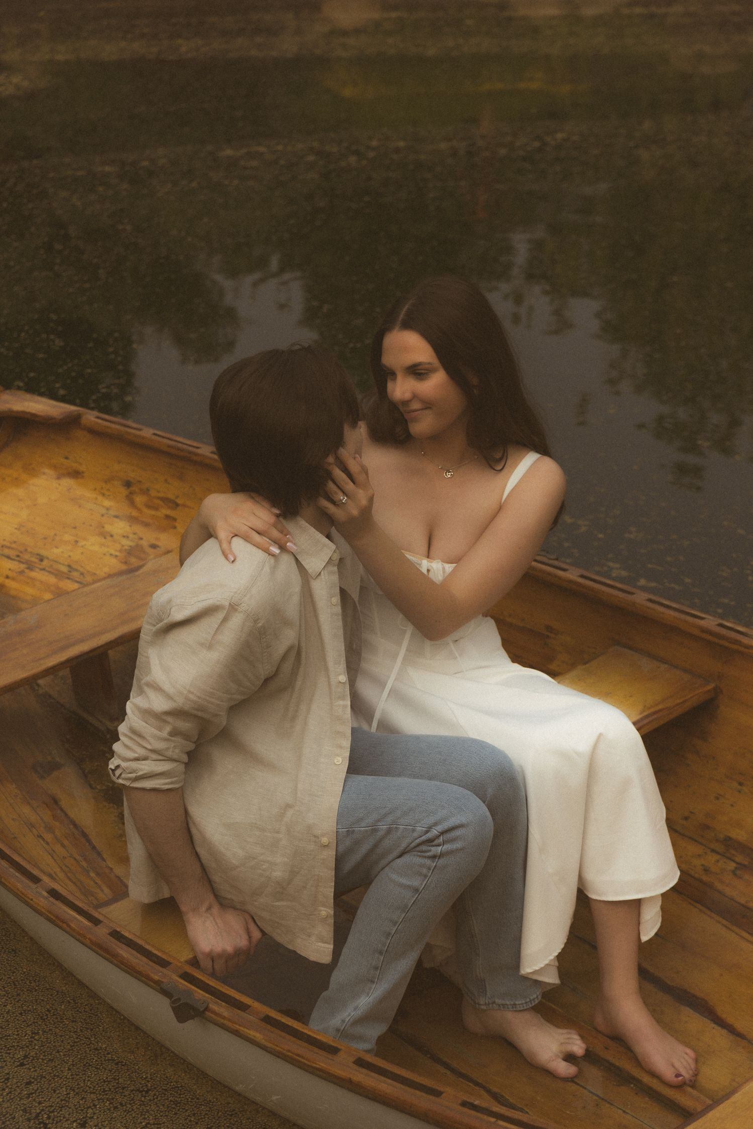 Romantic couple sitting in wooden rowboat by the water.