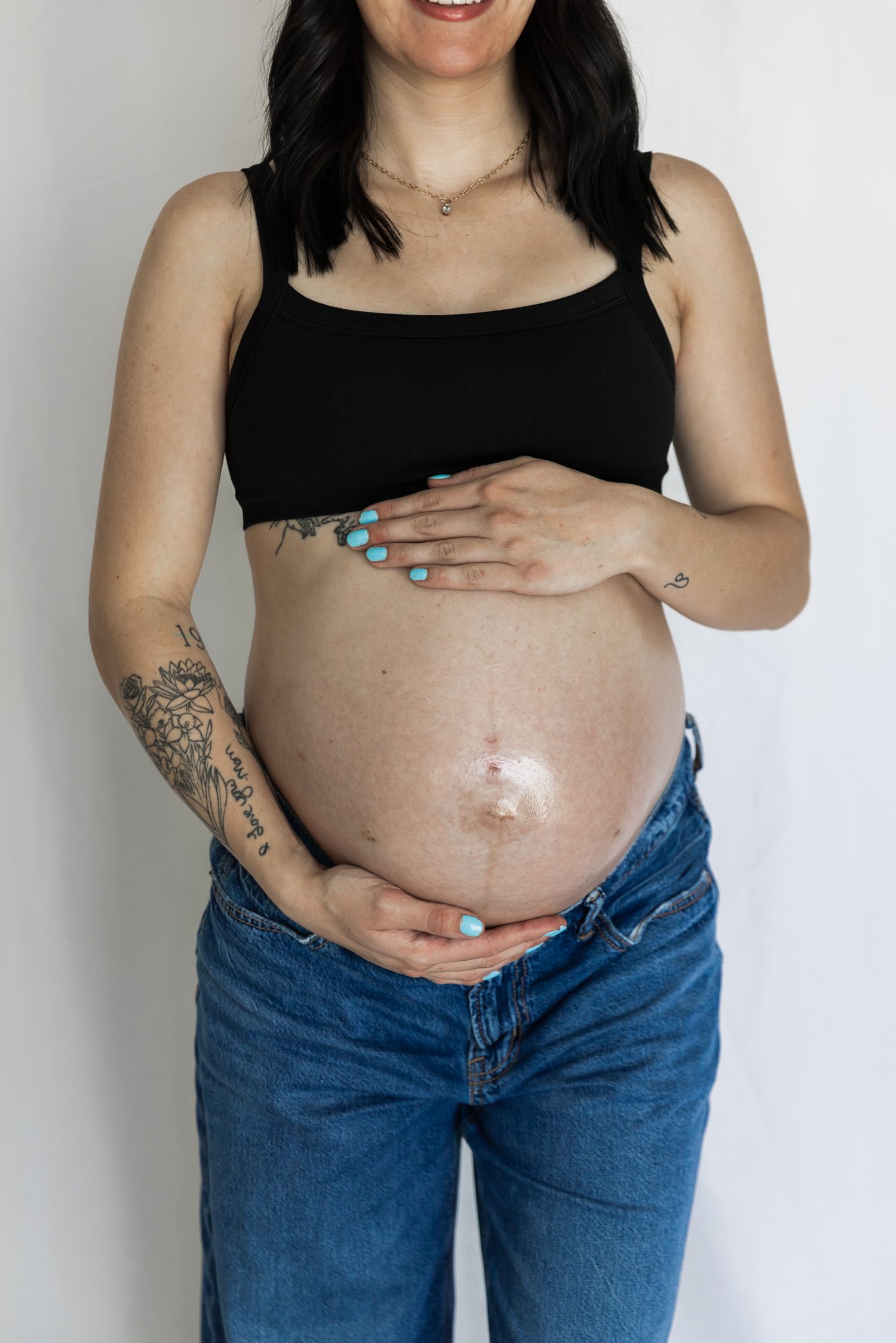 A progression of pregnancy photos showing a growing belly in jeans and black top against a white background.