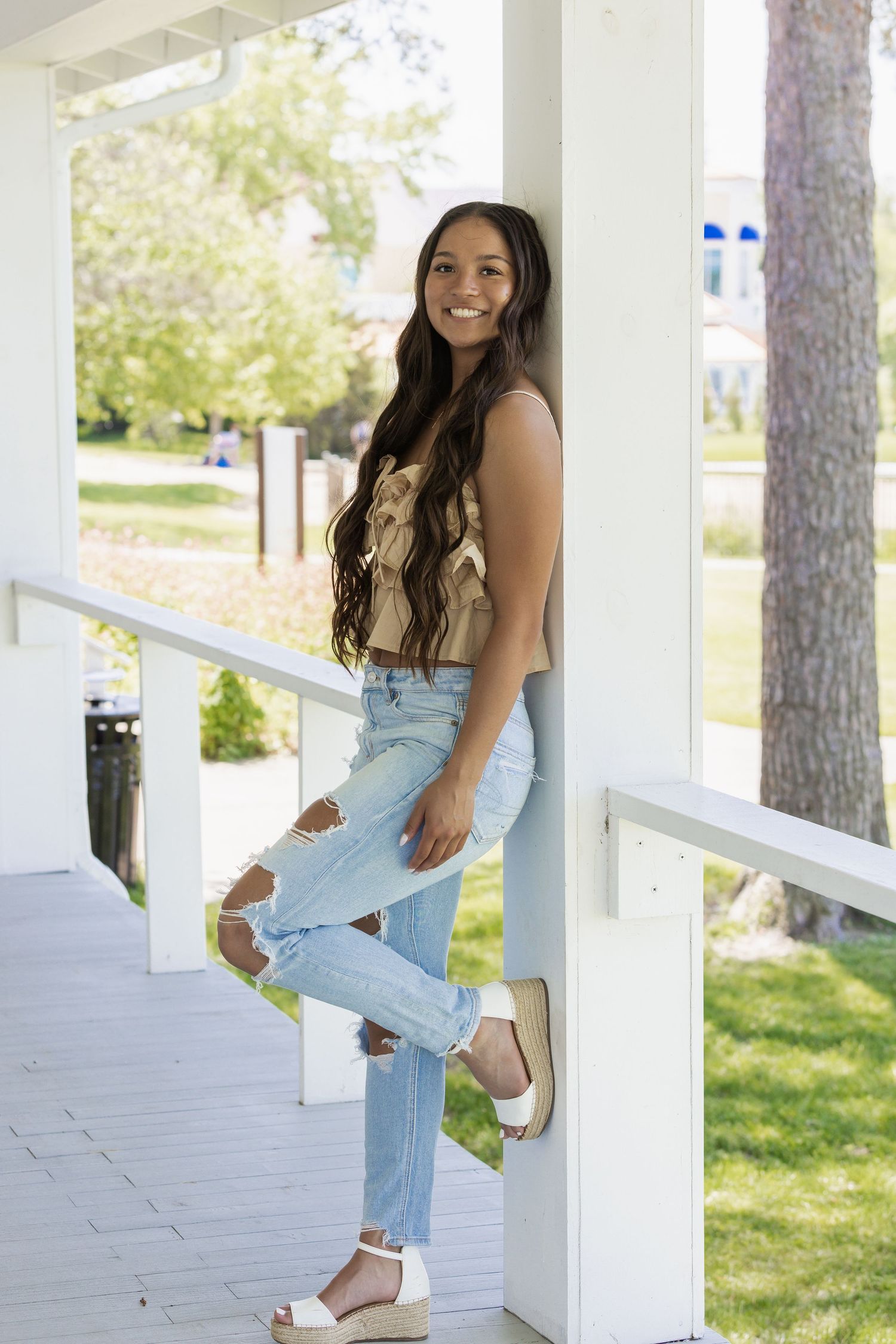 Casual summer outfit with ripped jeans on white porch with natural lighting.