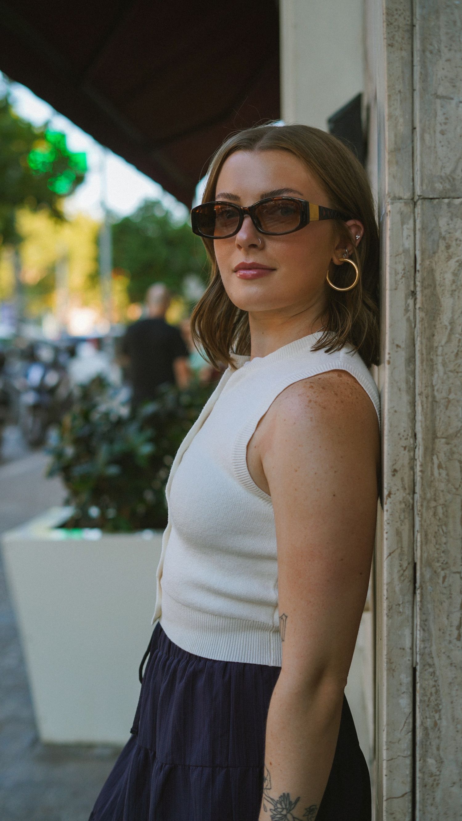 Fashion portraits showing white sleeveless top and navy skirt against stone column.
