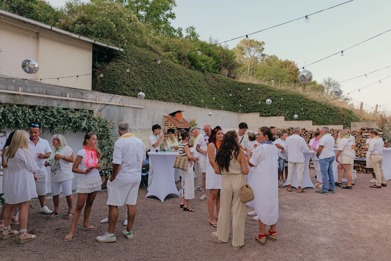 Fête d'anniversaire en extérieur, des invités discutent, cocktail dinatoire.
