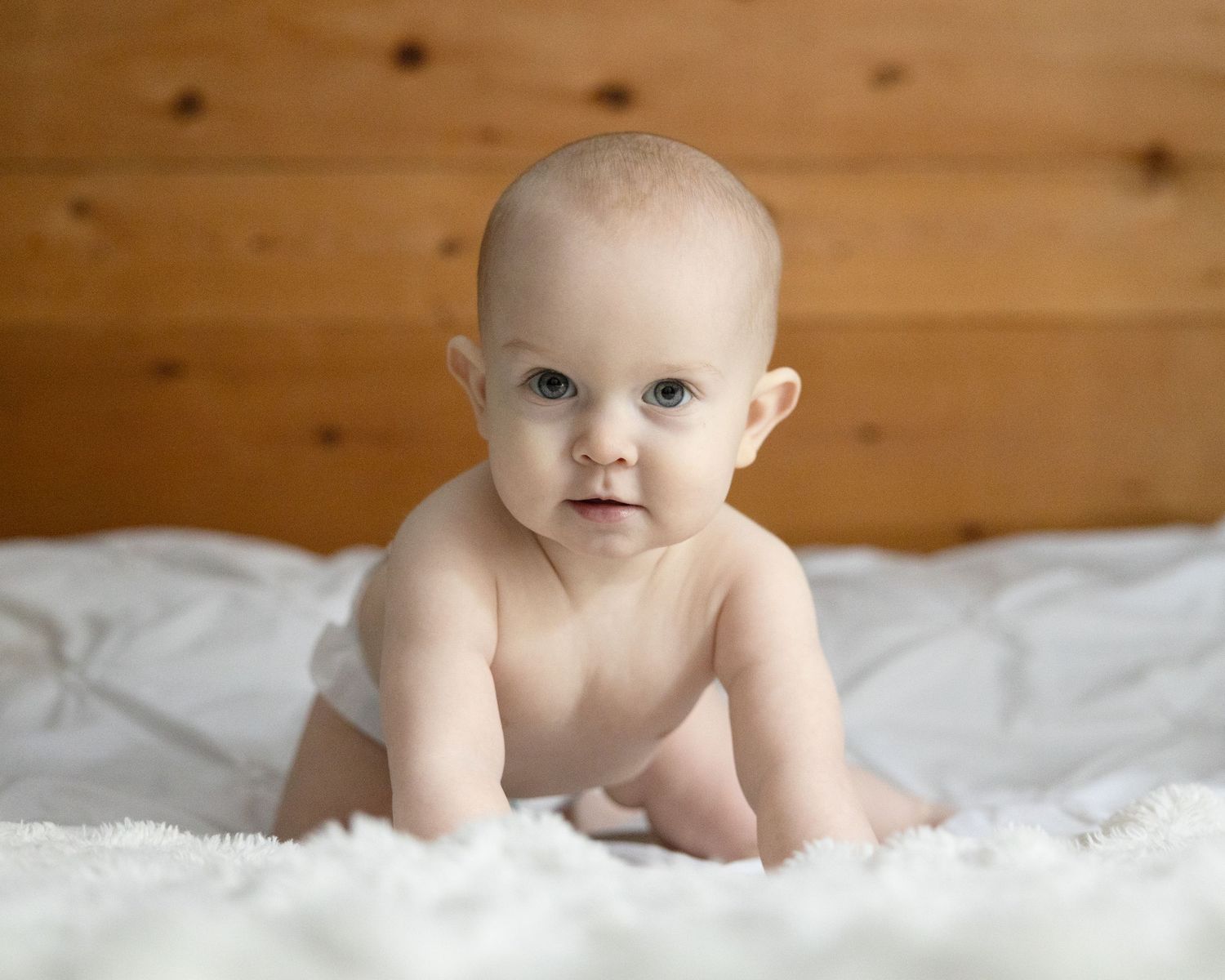 A baby crawling on a bed.