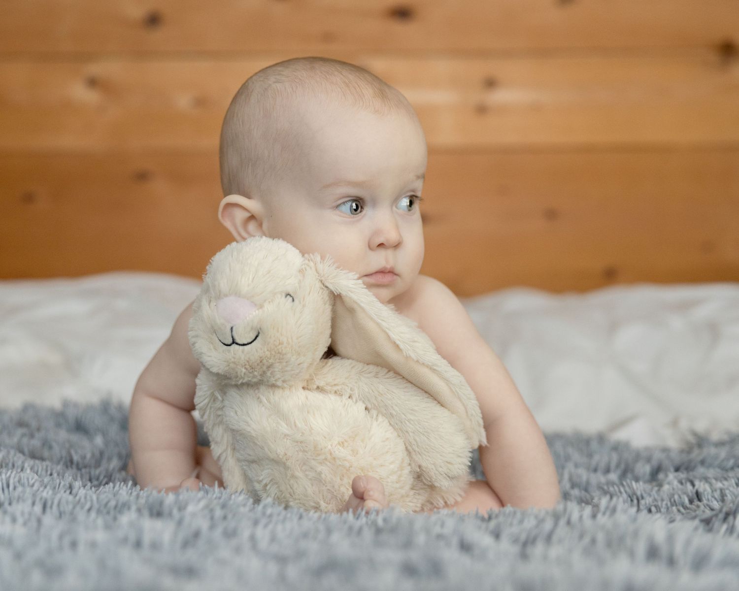 A baby holding a bunny for easter photos looking to the side.