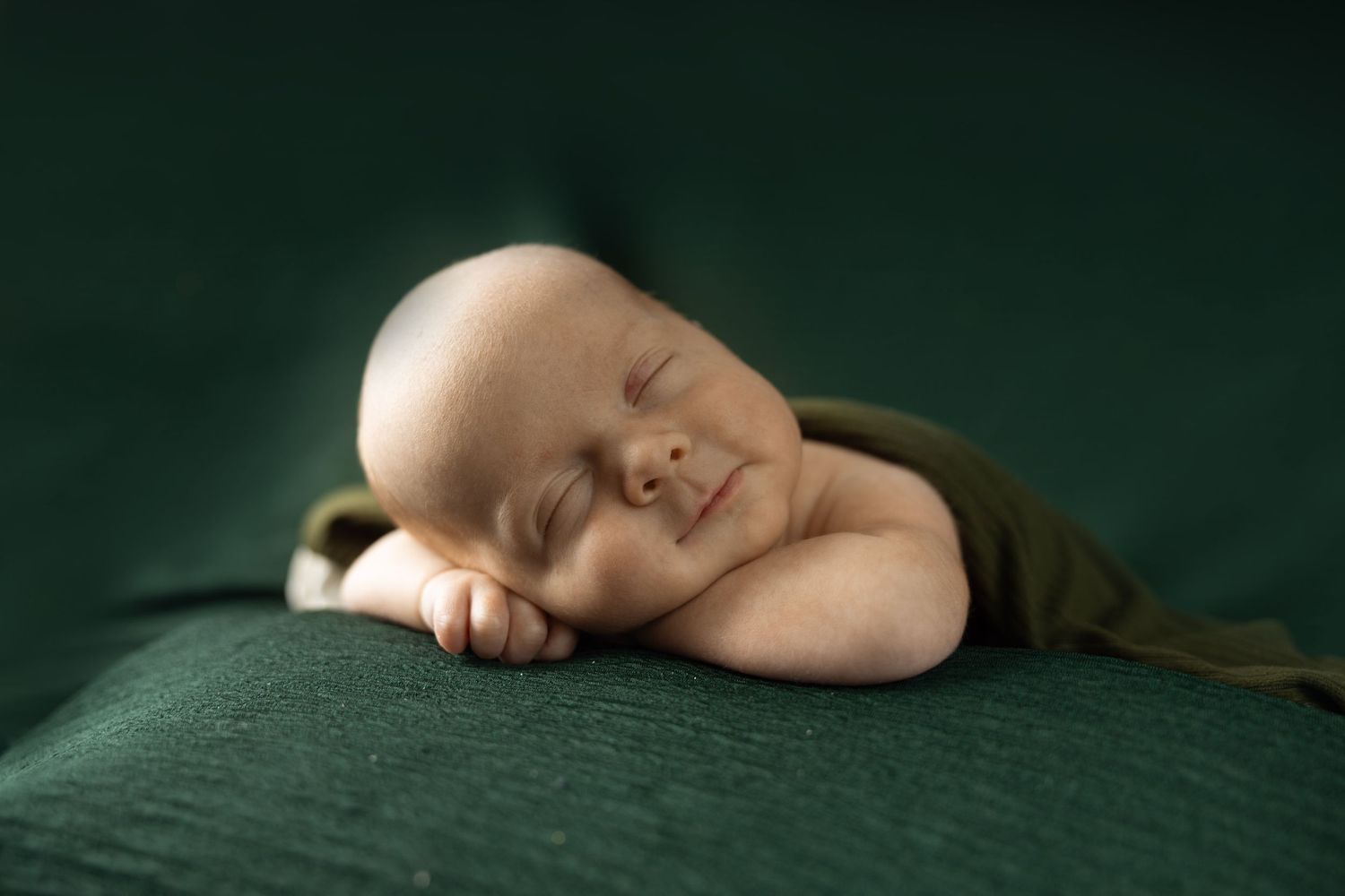 a baby posing during a newborn session while sleeping with a smirk on face.