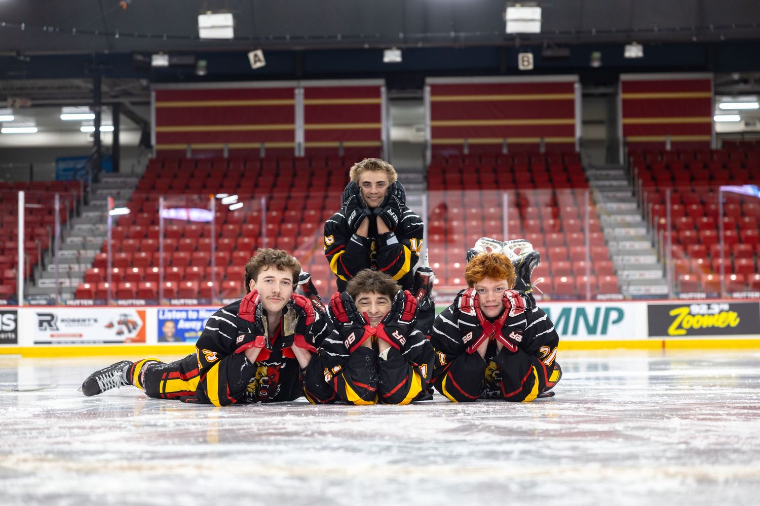 4 hockey players posing on the ice during a team photo day session.