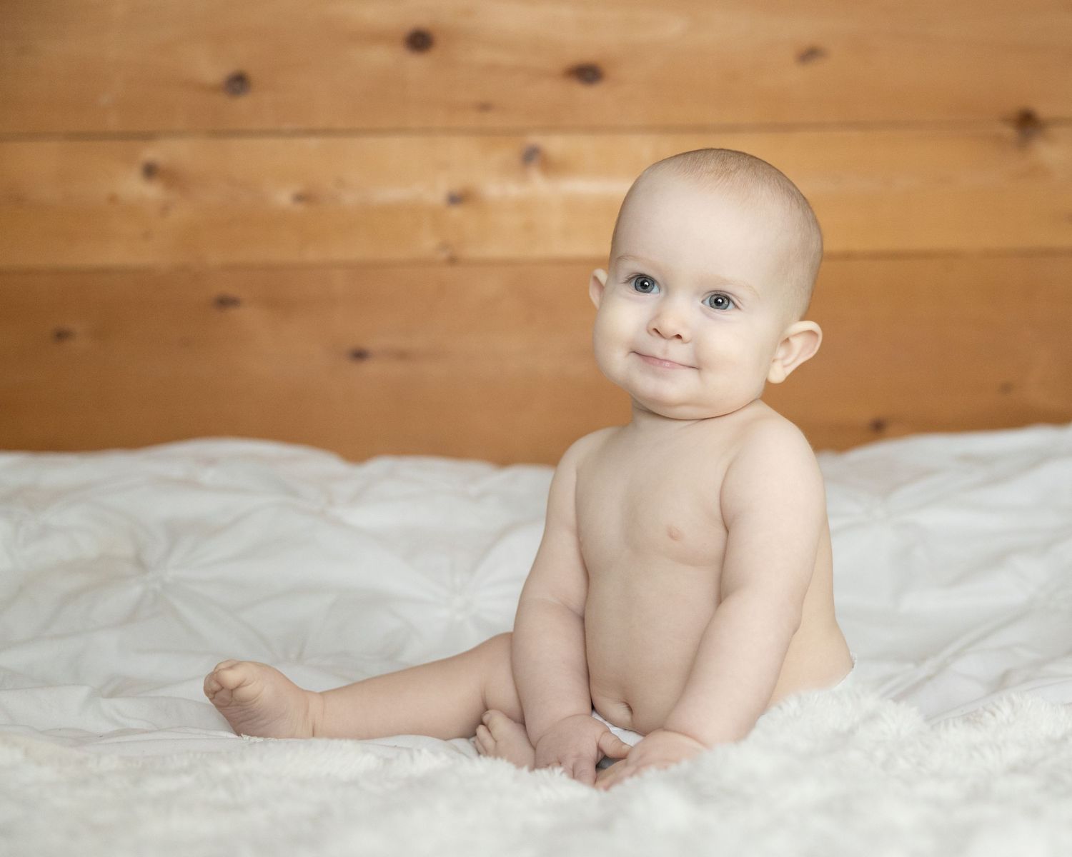 A baby sitting in a bed for a mini in home session.