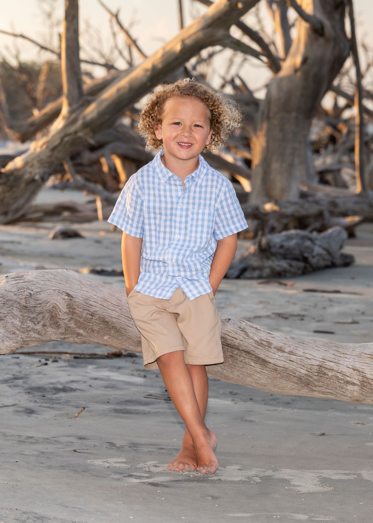 A young boy posing and smiling at the camera at Driftwood Beach.