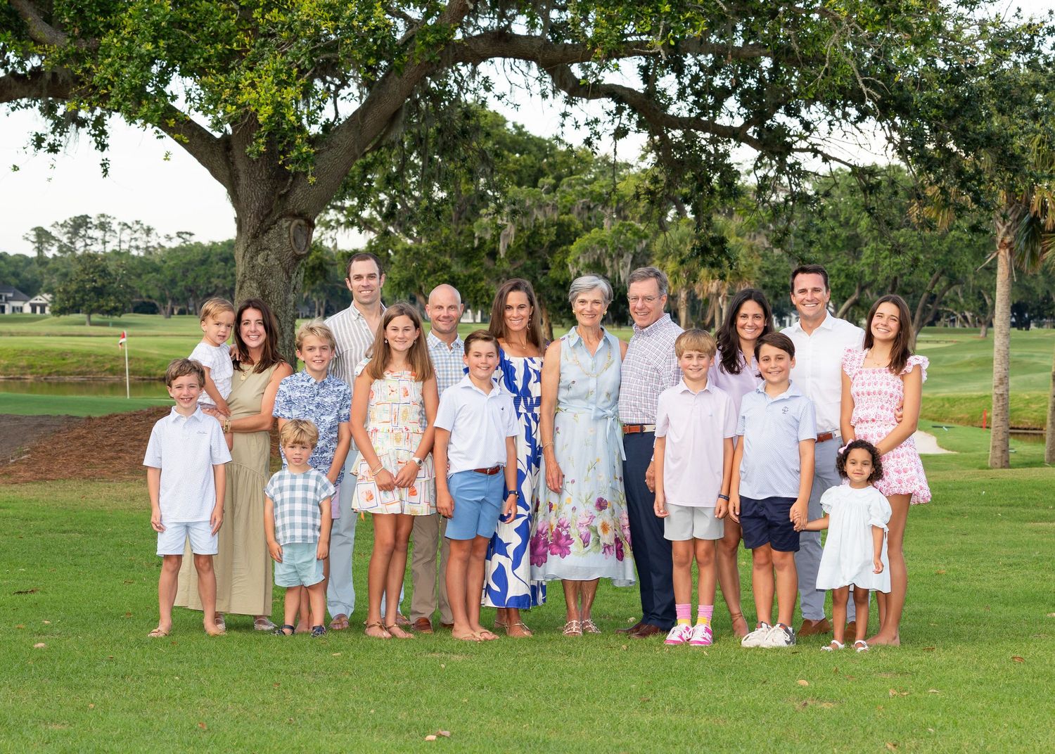 A family of 18 standing on a golf course, posed and smiling at the camera.
