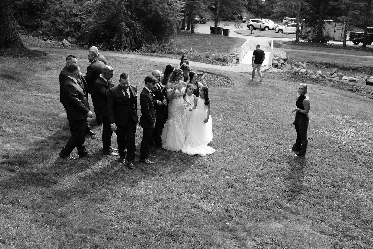 Aerial black and white photo of wedding party gathered on a grassy lawn during an outdoor ceremony.