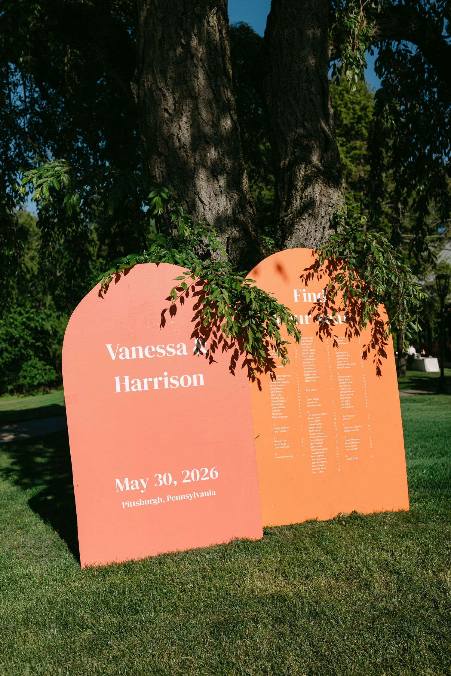 Orange arch-shaped wedding seating chart signs for Vanessa and Harrison, May 30, 2026, Pittsburgh PA.