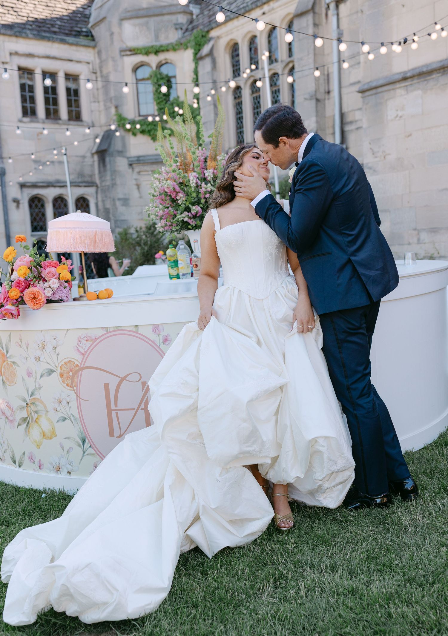 Bride and groom share a kiss outdoors at elegant wedding reception with floral decorations.