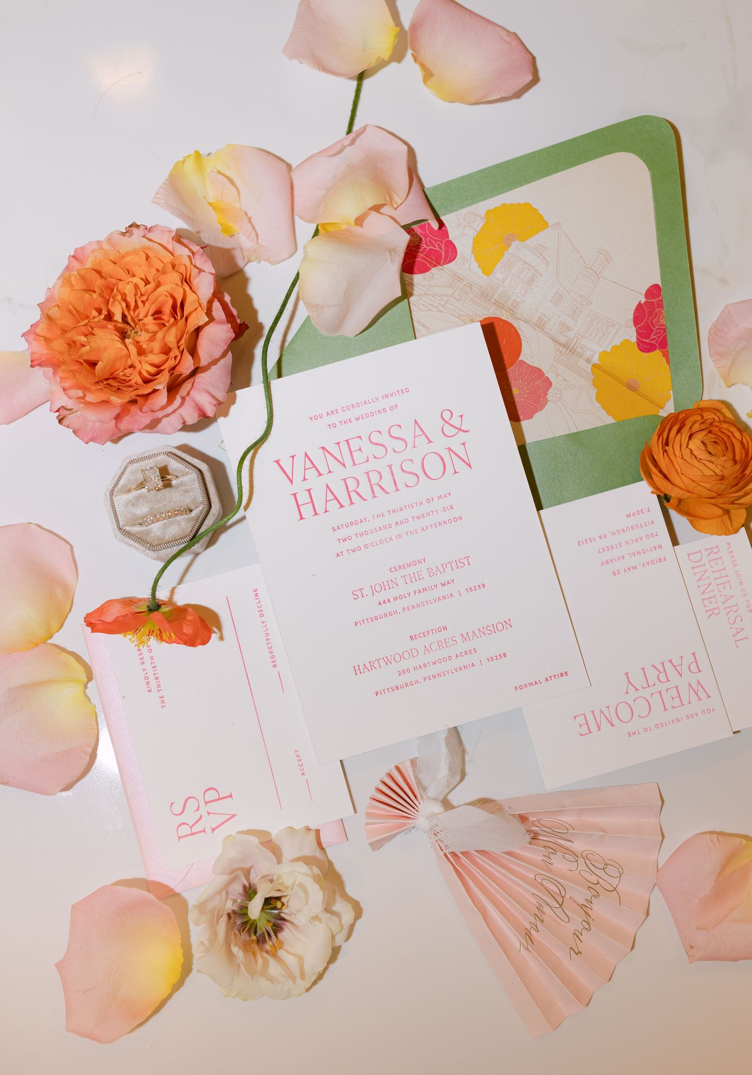 Colorful wedding invitation suite for Vanessa and Harrison surrounded by pink, orange, and yellow flowers and petals.