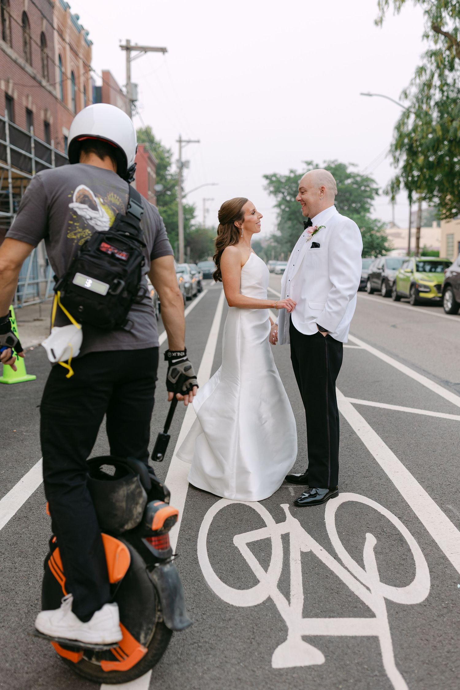 Bride and groom hold hands in a bike lane on a city street during their wedding portraits.