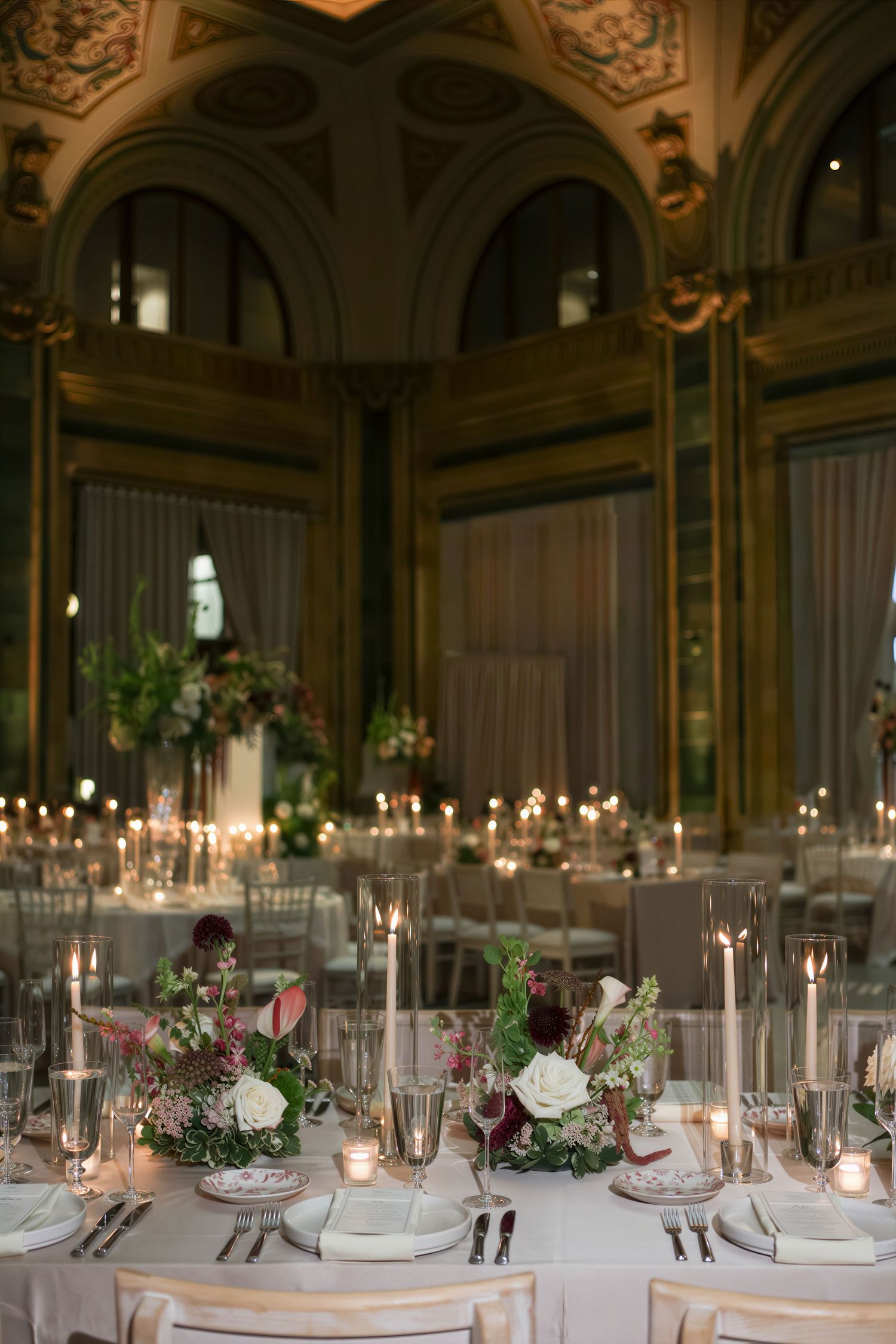 Elegant wedding reception at The Pennsylvanian in ornate ballroom with floral centerpieces, candles, and chiavari chairs.