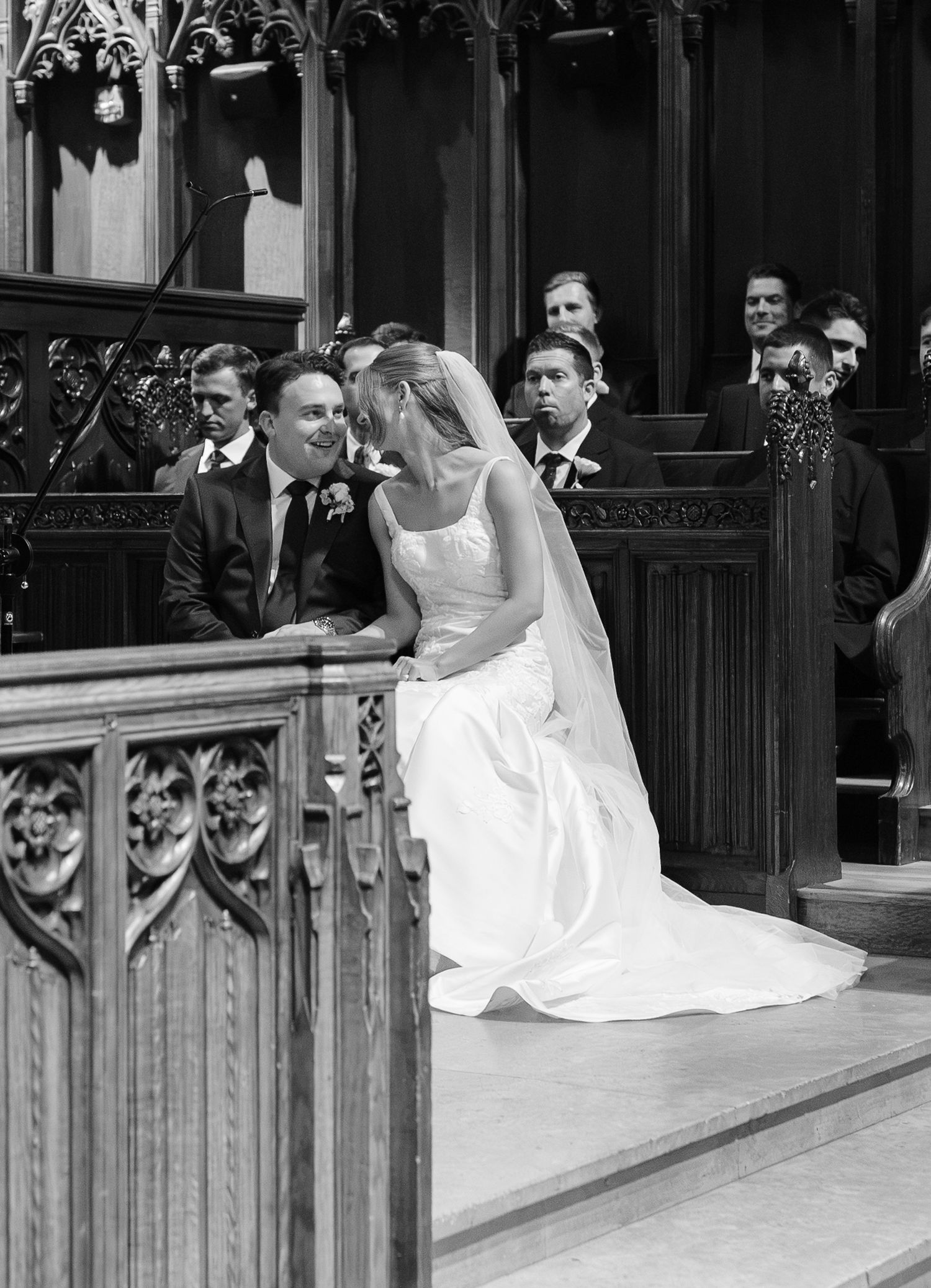 Black and white photo of bride and groom sharing a quiet moment during church wedding ceremony.